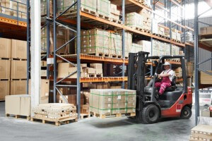 warehouse worker driver in uniform delivery and loading cardboxes by forklift stacker loader